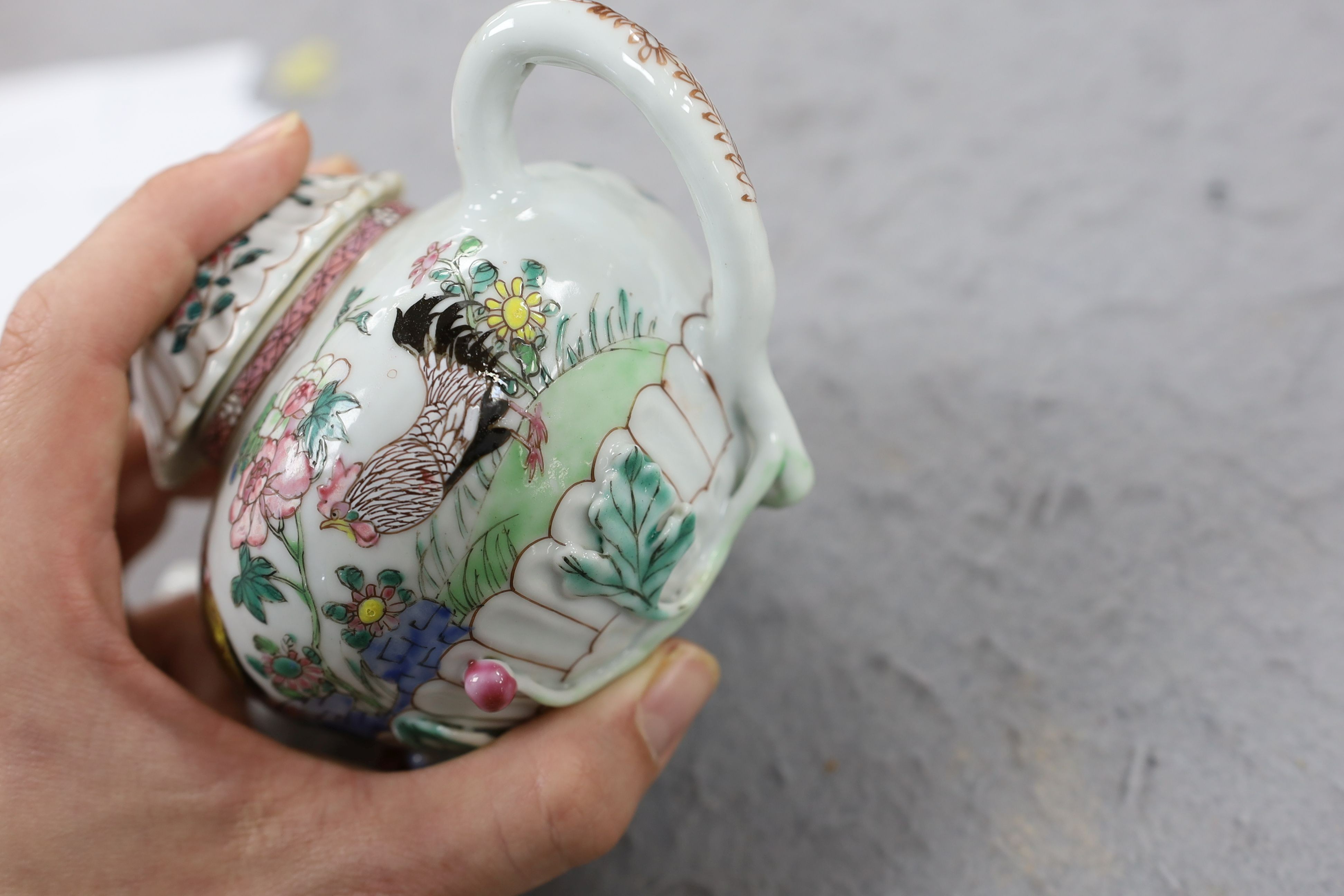A Chinese famille rose chrysanthemum moulded teapot, early Qianlong period, painted with a cockerel amongst flowers, on a cage work base, 10 cms high